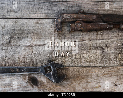 Festa del lavoro. Gli strumenti a mano e lettere in legno giacente sul tavolo. Vista superiore, close-up. Preparazione per la celebrazione. Congratulazioni ai cari, famiglia, Foto Stock