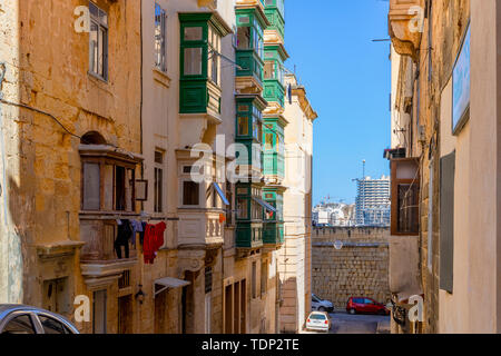 Tipica maltese strette strade con i tradizionali colorati finestre e persiane di legno e balconi, cielo blu chiaro su un giorno di estate, Valletta, Malta Foto Stock