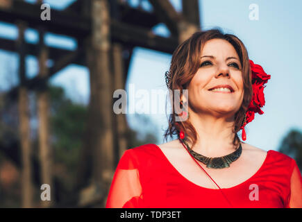 Close up ritratto di una bella donna ispanica di mezza età con abito rosso Foto Stock