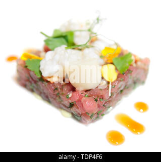 Elegante tartare di tonno con petali di fiori e salsa deliziosa isolato su bianco Foto Stock