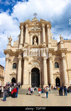 Siracusa, Sicilia, Italia - 10 Apr 2019: turisti nella parte anteriore del Duomo di Siracusa sulla Piazza Duomo. Famoso punto di riferimento e di attrazione turistica. Immagine verticale. Nuvole e parzialmente il cielo blu. Foto Stock