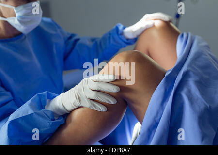 Chirurgo di esaminare la donna incinta durante la consegna in sala operatoria Foto Stock