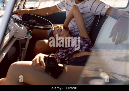 Bella donna di relax su uomo giro nel sedile anteriore del camper presso la spiaggia Foto Stock