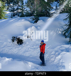 Donna con le racchette da neve sul cane di montagna sentiero con racchette da neve in North Vancouver; Vancouver, British Columbia, Canada Foto Stock