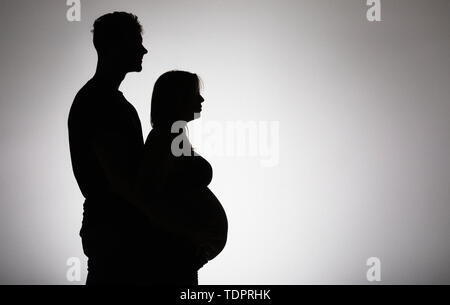 Una silhouette in uno studio di un giovane che stanno avendo un bambino e la madre è ben lungo per la sua gravidanza; Edmonton, Alberta, Canada Foto Stock