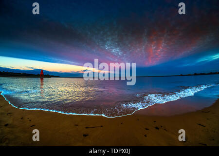 Mandria Groyne Faro e drammatico tramonto con nuvole incandescente e lavaggio di marea sulla spiaggia in primo piano; South Shields, Tyne and Wear, Inghilterra Foto Stock