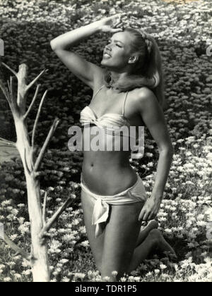 Attrice tedesca Solvi Stubing indossando un bikini in un campo a margherita, 1970s Foto Stock