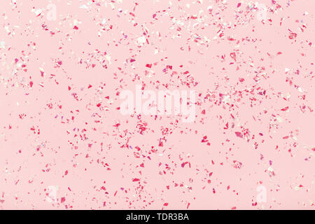 Glitter mica rosso brilla sul rosa pastello sfondo alla moda. Festosa cornice astratta. Lay piatto. Foto Stock