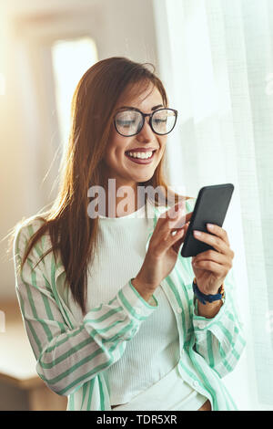 Il successo di un imprenditore femmina è la scrittura dei messaggi su uno smartphone in ufficio. Foto Stock