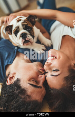 La giovane coppia felice si trasferisce in una nuova casa. Sono sdraiato sul pavimento con il loro piccolo cucciolo dopo che avevano portato a caselle con cose da th Foto Stock