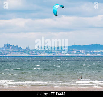 Longniddry Bents, Firth of Forth, Scotland, Regno Unito, 18 giugno 2019. Regno Unito: Meteo kite surfers hanno condizioni ideali a bassa marea con un forte vento e sole in discontinuo Firth of Forth guardando verso il distintivo skyline di Edimburgo attraverso la baia Foto Stock