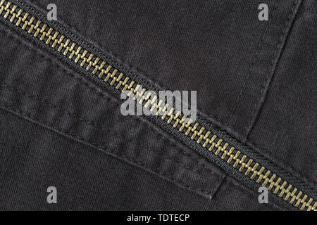 Chiusura a zip in ottone sul Jeans nero lo sfondo di texture. Chiusura zip in ottone sul Jeans nero Texture di sfondo Design Abbigliamento Foto Stock