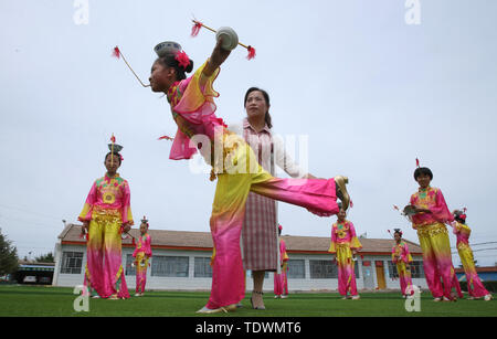 Gansu Gansu, Cina. Xx Giugno, 2019. Gansu, Cina - 20 Giugno 2019: l'erede del patrimonio culturale immateriale è istruire i bambini per eseguire il non-l'eredità genetica programma a proposito della pagoda di ciotola danza nel parco giochi di minle imbarco scuola primaria di minle county, zhangye città, provincia di Gansu.Minleding pagoda di ciotola di danza folk combina le acrobazie con la danza, che riflette una sorta di danza composta, eseguita e goduto dagli antichi soldati e civili, usando tazze di riso come puntelli e materiali locali nel loro lavoro. Credito: ZUMA Press, Inc./Alamy Live News Foto Stock