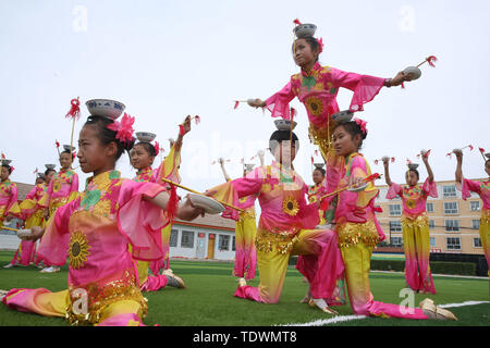 Gansu Gansu, Cina. Xx Giugno, 2019. Gansu, Cina - 20 Giugno 2019: l'erede del patrimonio culturale immateriale è istruire i bambini per eseguire il non-l'eredità genetica programma a proposito della pagoda di ciotola danza nel parco giochi di minle imbarco scuola primaria di minle county, zhangye città, provincia di Gansu.Minleding pagoda di ciotola di danza folk combina le acrobazie con la danza, che riflette una sorta di danza composta, eseguita e goduto dagli antichi soldati e civili, usando tazze di riso come puntelli e materiali locali nel loro lavoro. Credito: ZUMA Press, Inc./Alamy Live News Foto Stock