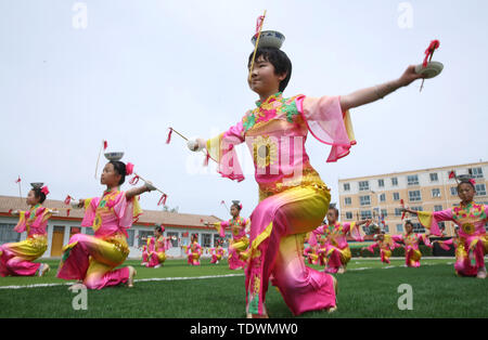 Gansu Gansu, Cina. Xx Giugno, 2019. Gansu, Cina - 20 Giugno 2019: l'erede del patrimonio culturale immateriale è istruire i bambini per eseguire il non-l'eredità genetica programma a proposito della pagoda di ciotola danza nel parco giochi di minle imbarco scuola primaria di minle county, zhangye città, provincia di Gansu.Minleding pagoda di ciotola di danza folk combina le acrobazie con la danza, che riflette una sorta di danza composta, eseguita e goduto dagli antichi soldati e civili, usando tazze di riso come puntelli e materiali locali nel loro lavoro. Credito: ZUMA Press, Inc./Alamy Live News Foto Stock