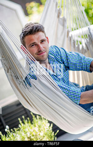 Giovane uomo seduto in un sedile pensile, Germania Foto Stock