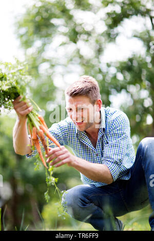 Uomo con un bunsh di appena raccolto le carote dal proprio giardino, Germania Foto Stock
