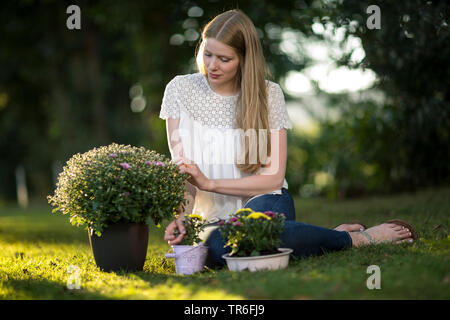Giovane donna bionda seduta con gli astri su un prato, Germania Foto Stock