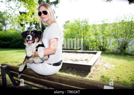 Pastore australiano (Canis lupus f. familiaris), donna bionda con un cucciolo sul giro, Germania Foto Stock