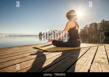 Donna facendo esercizi yoga presso un lago, in Germania, in Baviera Foto Stock