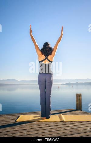 Donna facendo esercizi yoga presso un lago, in Germania, in Baviera Foto Stock