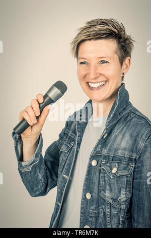 Bella Donna sorridente con un microfono, Germania Foto Stock