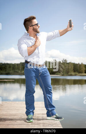 Attraente ione uomo vacanza al lago Starnberg, facendo un selfie, in Germania, in Baviera Foto Stock