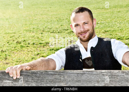 Uomo in Baviera abbigliamento tradizionale in un recinto di pascolo, in Germania, in Baviera Foto Stock