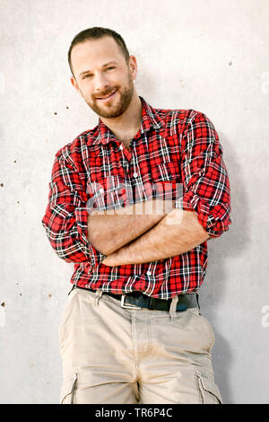 Uomo bello con gonna a scacchi in piedi a una facciata, Germania Foto Stock