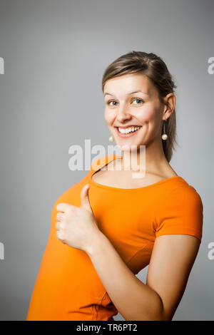 Giovane donna felice, che frolicsome mostrando pollice in alto, Germania Foto Stock