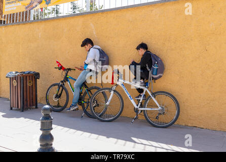 Eskisehir/Turkey-April 23 2019: due studenti maschi parete pendente, sedersi e rilassarsi sulla moto e controllare i loro telefoni cellulari. Foto Stock