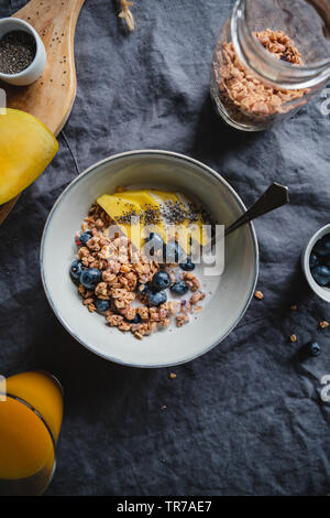 Vista superiore del tavolo per la colazione, crunchy granola con frutti di bosco freschi e crema di latte o latte. Appartamento laico, mangiare sano. Foto Stock