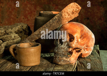 Still Life fotografia, cranio umano con il vecchio coltello sulla sua fronte Foto Stock