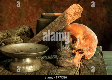 Still Life fotografia, cranio umano con il vecchio coltello sulla sua fronte Foto Stock