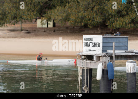 Un uomo si siede tranquillamente in un kayak vicino alla riva dell'area interna del porto, Balmoral Beach a Sydney, Australia Foto Stock