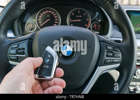 Sankt-Petersburg Russia, 4 Aprile 2018: mano d'uomo in possesso di un accesso wireless a BMW X5 F15 chiave auto in cuoio nero per interni auto. Auto moderna particolari degli interni. C Foto Stock