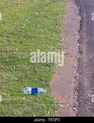 Una bottiglia di plastica si trova gettato su un marciapiede accanto a una strada pubblica immagine con spazio di copia Foto Stock