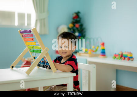 Asian Toddler baby boy impara a contare. Carino bambino che gioca con abacus giocattolo. Little Boy divertirsi al chiuso in casa. Il concetto educativo per il Toddler bab Foto Stock