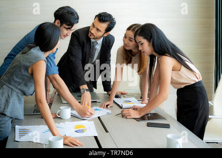 Smart manager spiegando riunione interna al suo team di progetto in un ufficio moderno. La multi etnico persona business group in tuta. Progetto e Business c Foto Stock