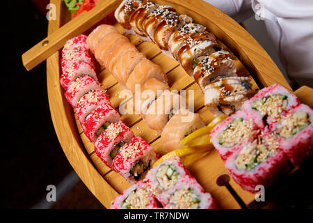 Sushi set su una barca di legno nelle mani del cuoco. Foto Stock