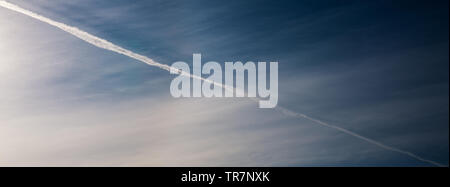 I gas di scarico del motore contrails nel cielo blu. Foto Stock