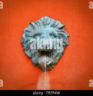 Faccia statua testa leone sulla parete arancione - Fontana del flusso di acqua dalla bocca statua di Lion Foto Stock