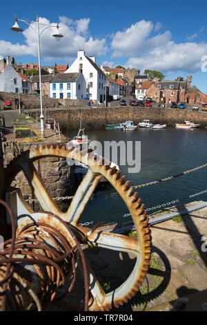 Città di Crail, Scozia. Il pittoresco sunny view arrugginite ingranaggio di sollevamento su Crail harbour parete. Foto Stock