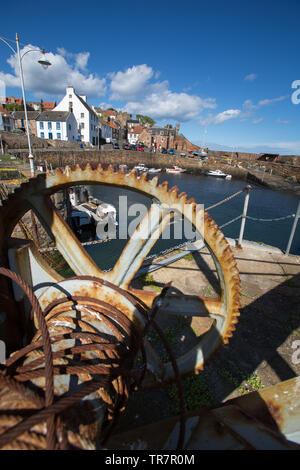 Città di Crail, Scozia. Il pittoresco sunny view arrugginite ingranaggio di sollevamento su Crail harbour parete. Foto Stock