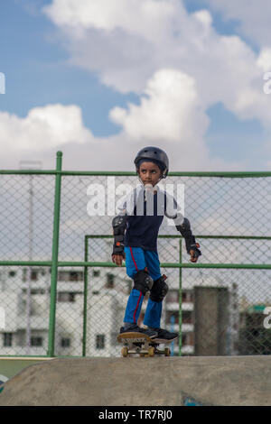 Un ragazzo indiano preparando andare giù per una rampa da skateboard Foto Stock