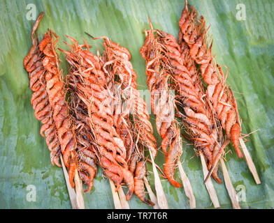 Acqua dolce piccoli scampi alla griglia con croccante stick e condimento su foglia di banano in street market alimentare Foto Stock