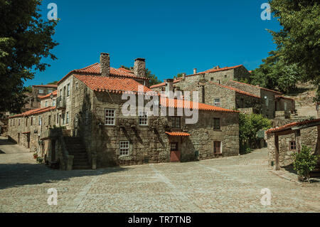 Case gotiche in pietra con alberi frondosi e deserte vicolo sul pendio a Sortelha. Un sorprendente e ben conservato borgo medievale in Portogallo. Foto Stock