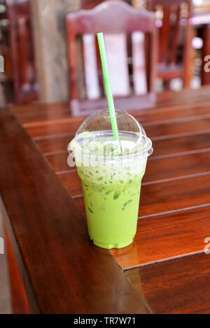 Iced tè verde in una tazza di plastica tè verde Matcha latte frappé e paglia sulla tavola in coffee shop Foto Stock