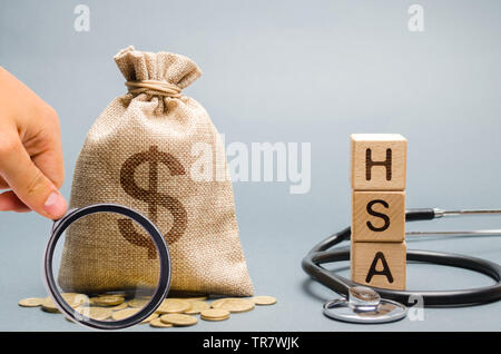 Blocchi di legno con la parola HSA e denaro borsa con stetoscopio. Salute Conto di risparmio. Assistenza sanitaria. Assicurazione sanitaria. Gli investimenti. Tax-free medical e Foto Stock