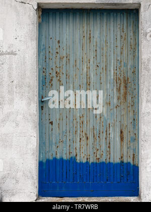 Close-up di rusty grigio e blu la porta di metallo con peeling di vernice e di parete a spiovente. Foto Stock